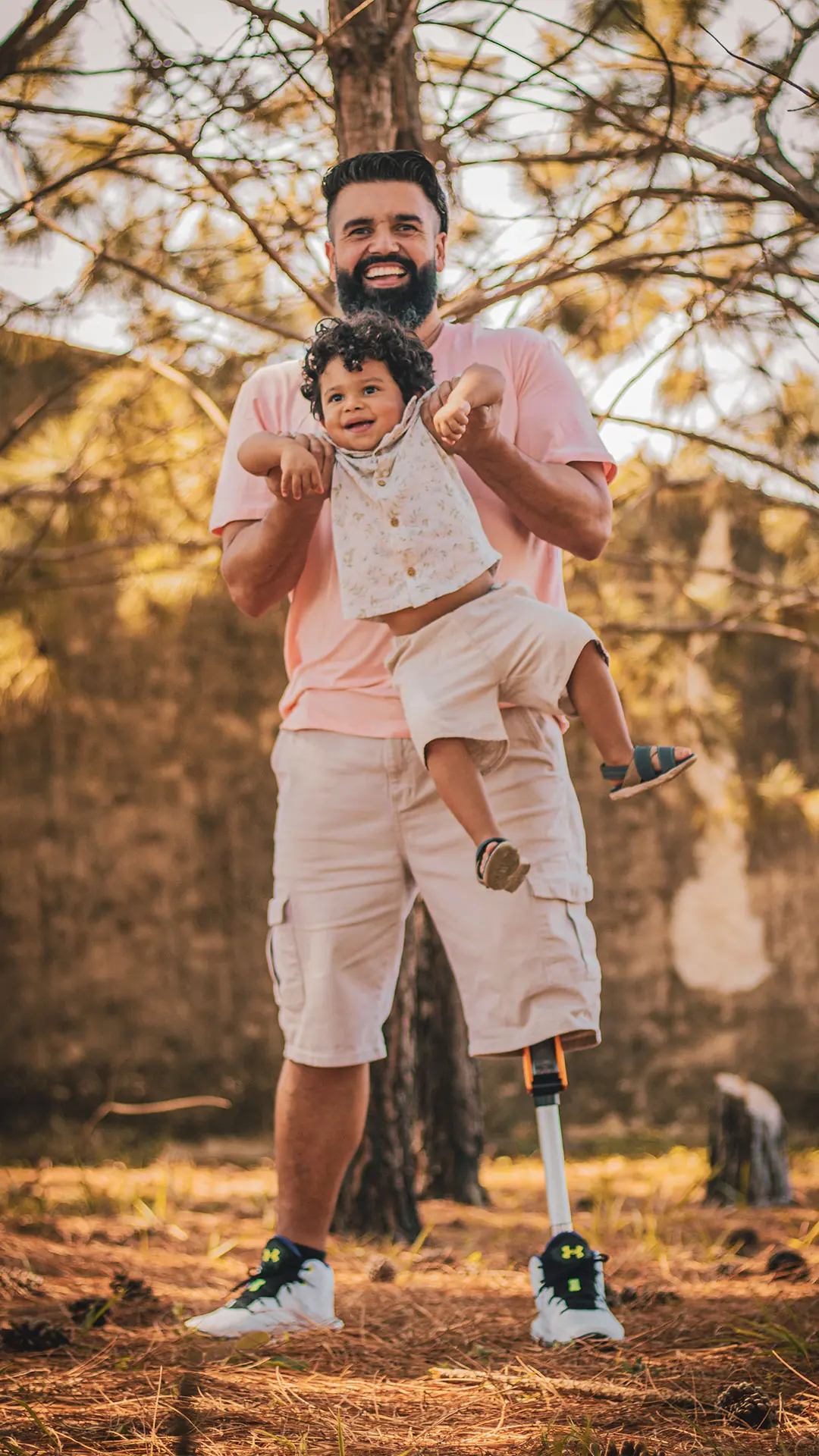 Отец с протезом ноги держит сына на руках в роще
